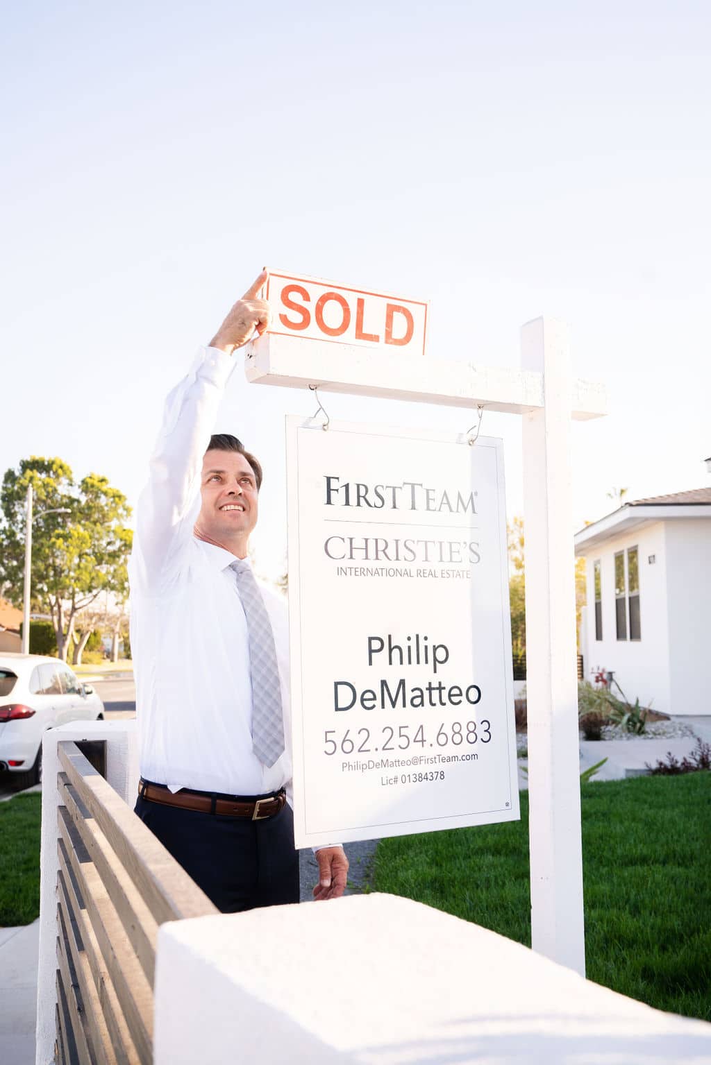 Philip deMatteo hanging a sold sign rider on a for sale sign