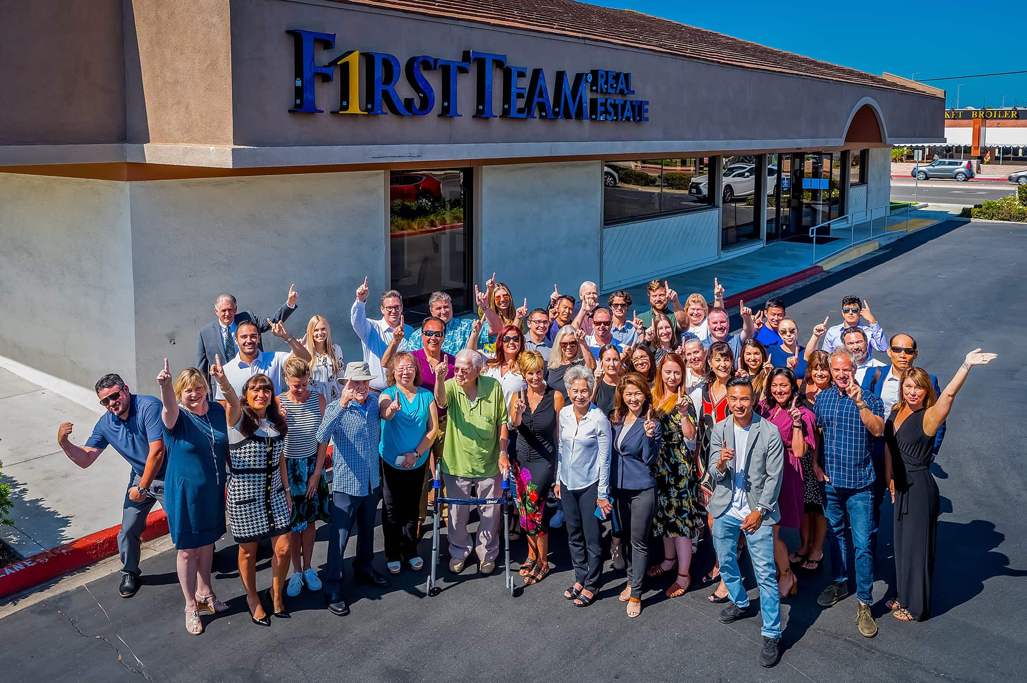 First Team Huntington Beach South agents gathered outside office with hands up 