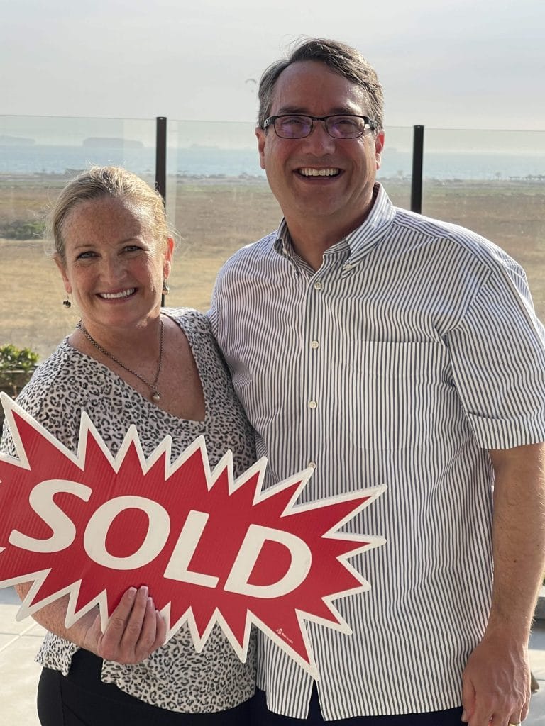 Dale Giali and Susan Westover-Giali holding red sold sign