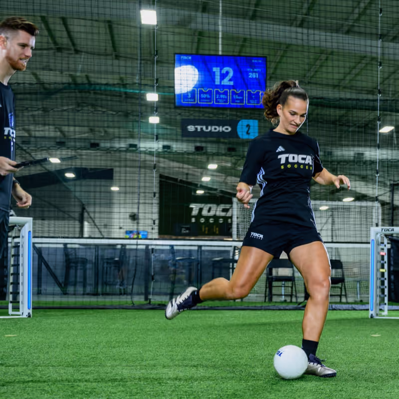 Player practicing soccer skills with TOCA Touch Trainer, an automated ball delivery system for precision training.