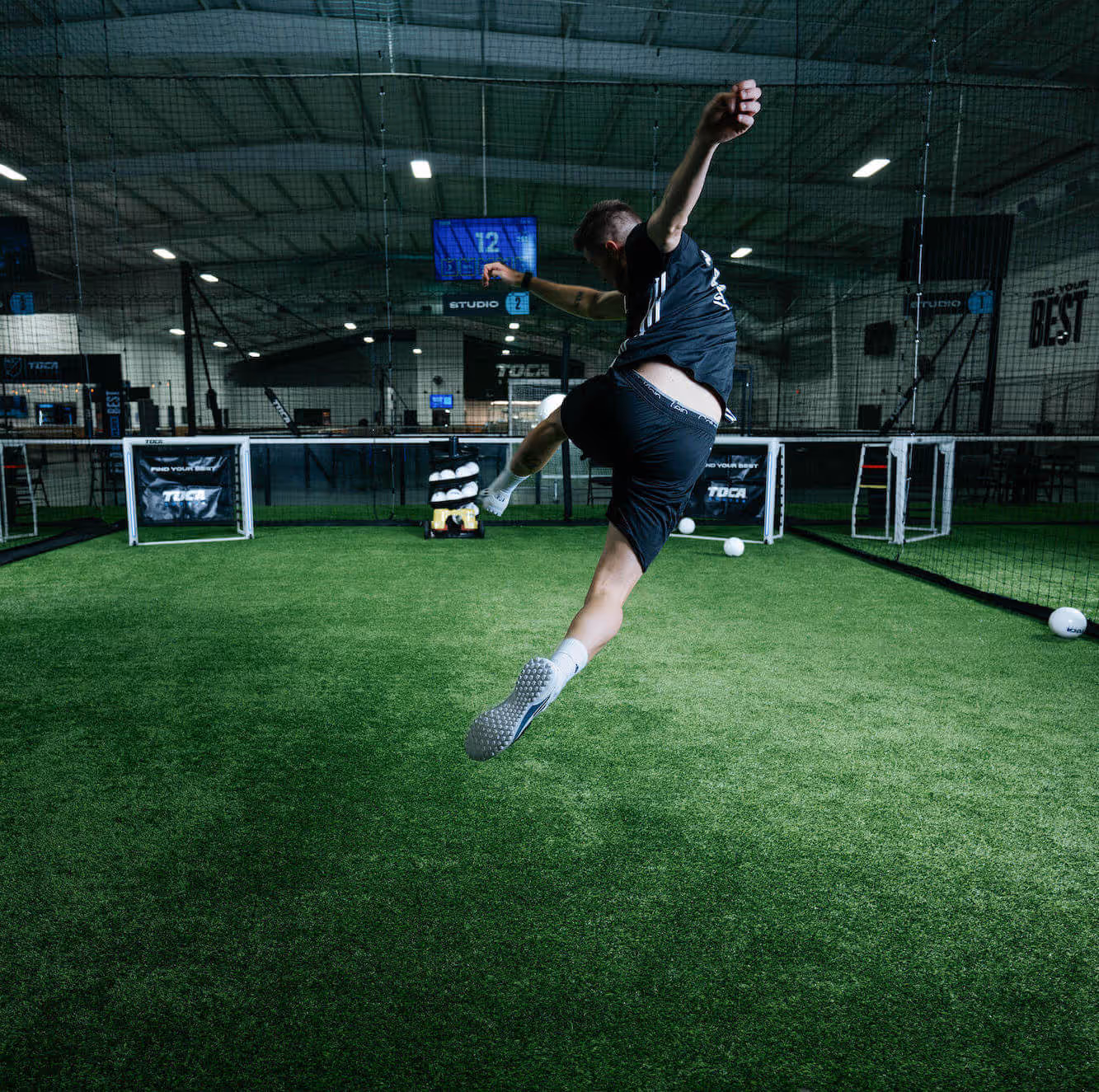Soccer player kicking ball switfly into technology enabled goal.