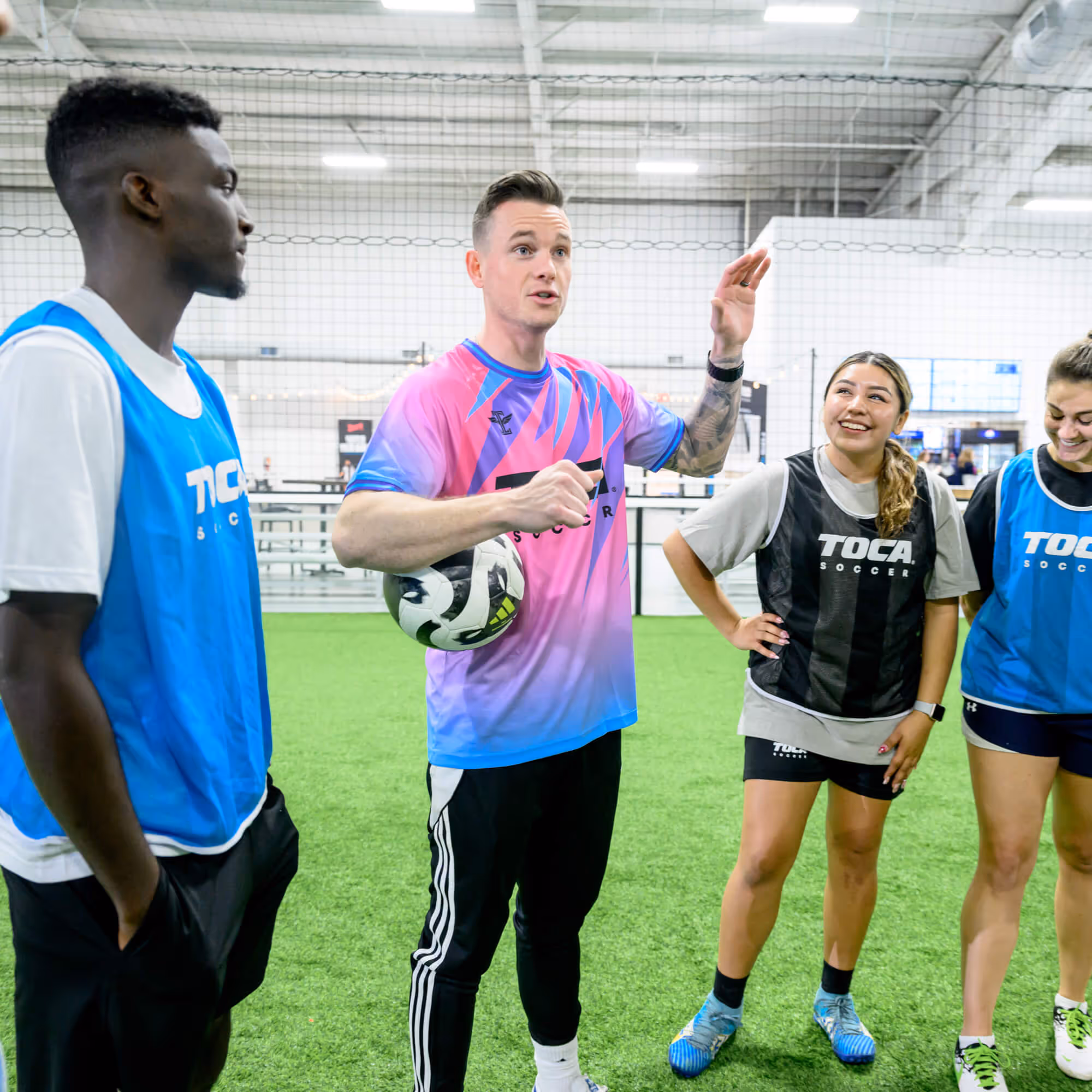 Soccer coach giving feedback to pickup soccer players on a TOCA indoor soccer field.