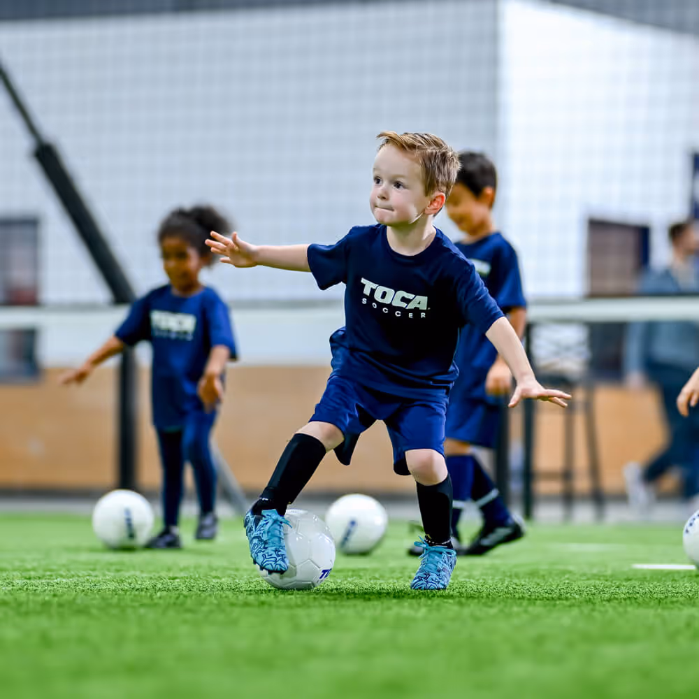 A young soccer playing practicing with soccer ball dribbling.