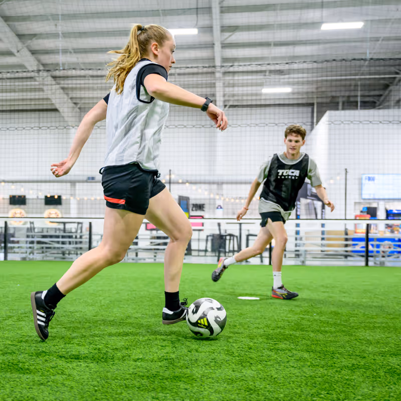 Two adult pickup soccer players competing on an indoor soccer field.