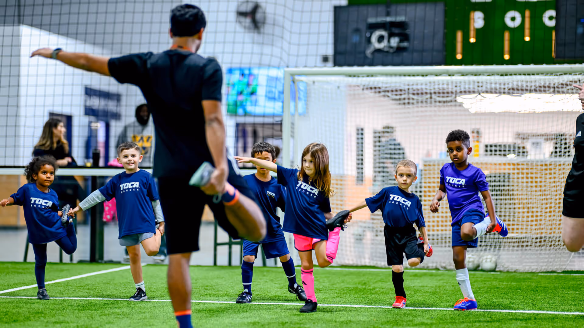 Kids at a TOCA Soccer camp warming up before playing on the indoor soccer field.