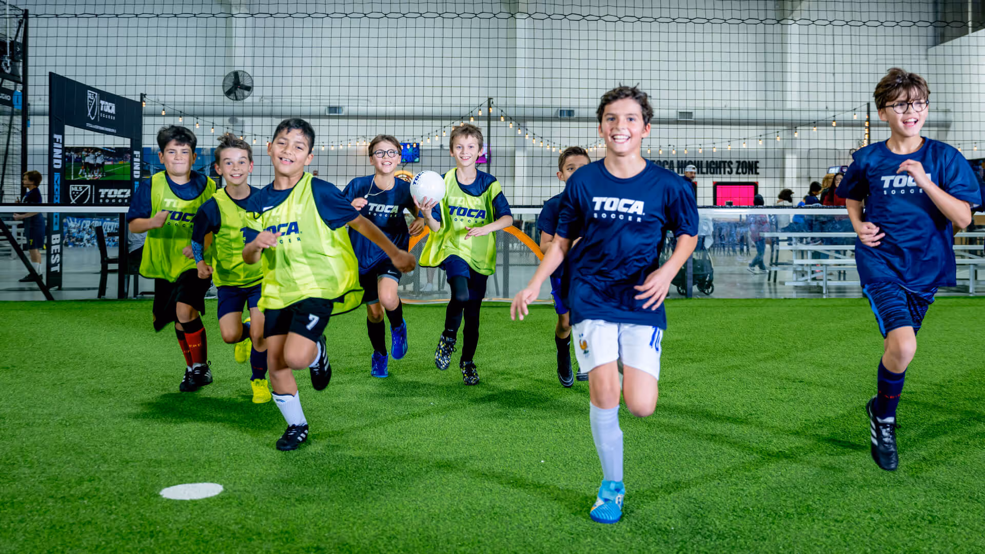 Kids TOCA soccer classes players running on indoor soccer field.