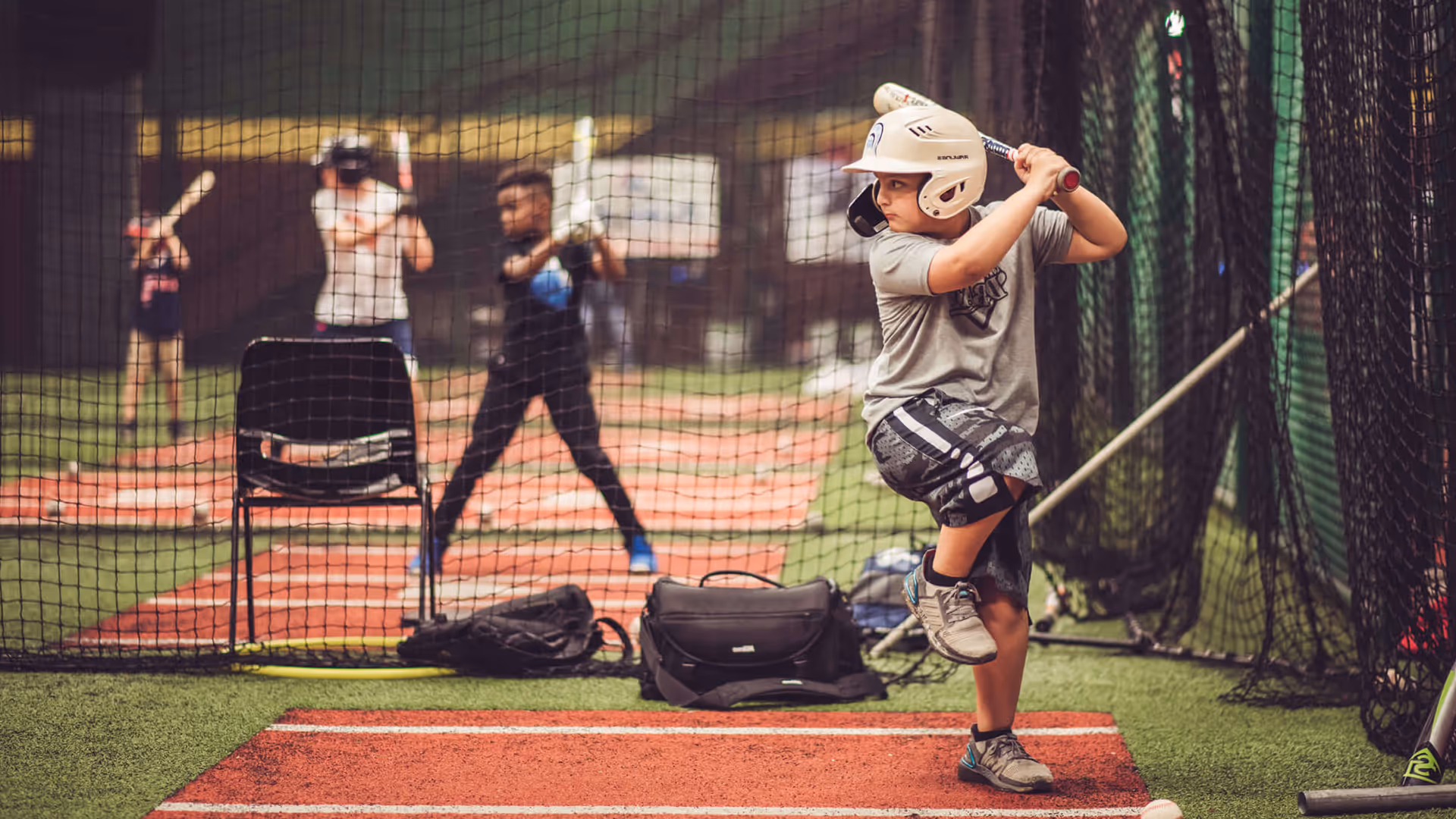 Young baseball players sharpening their swings together in a TOCA indoor training facility, having fun while practicing and building skills.