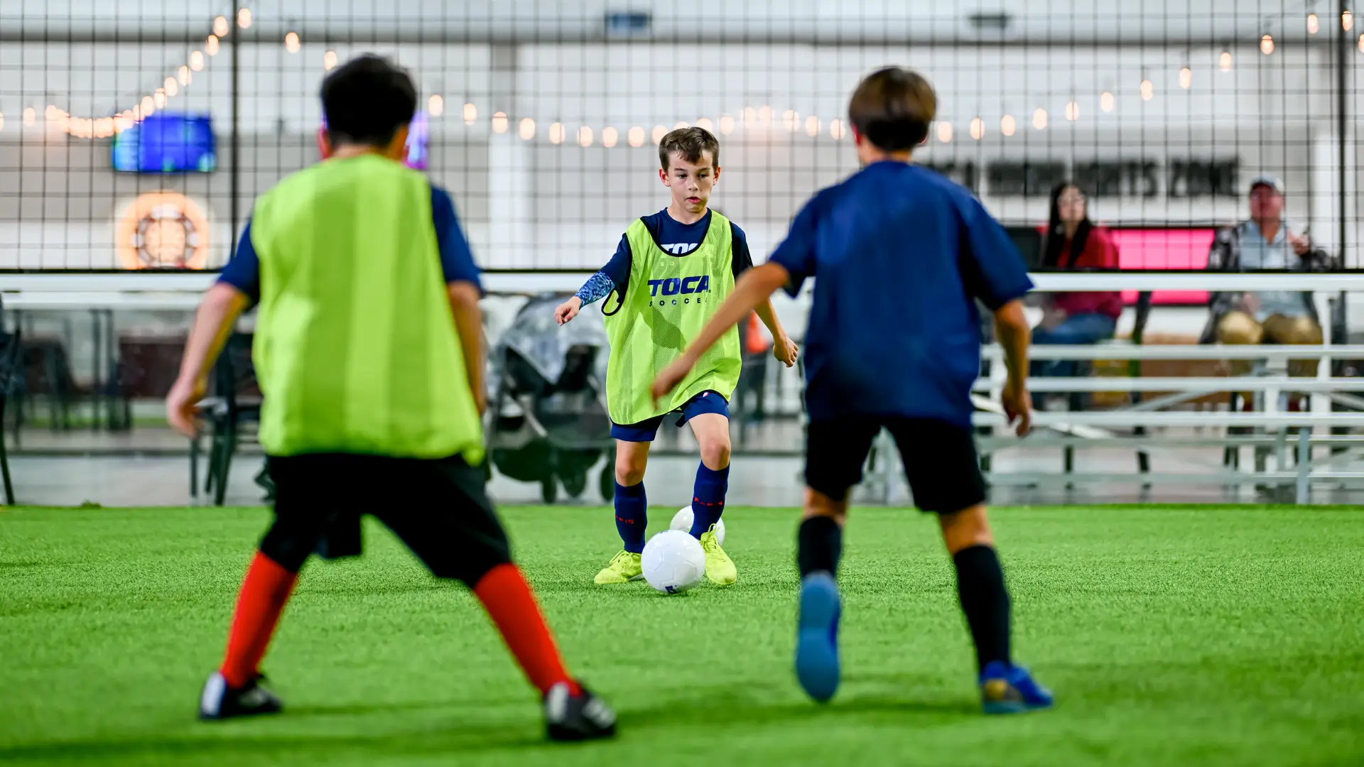 Young soccer player dribbling past defenders in a small-sided game on outdoor turf at TOCA Soccer