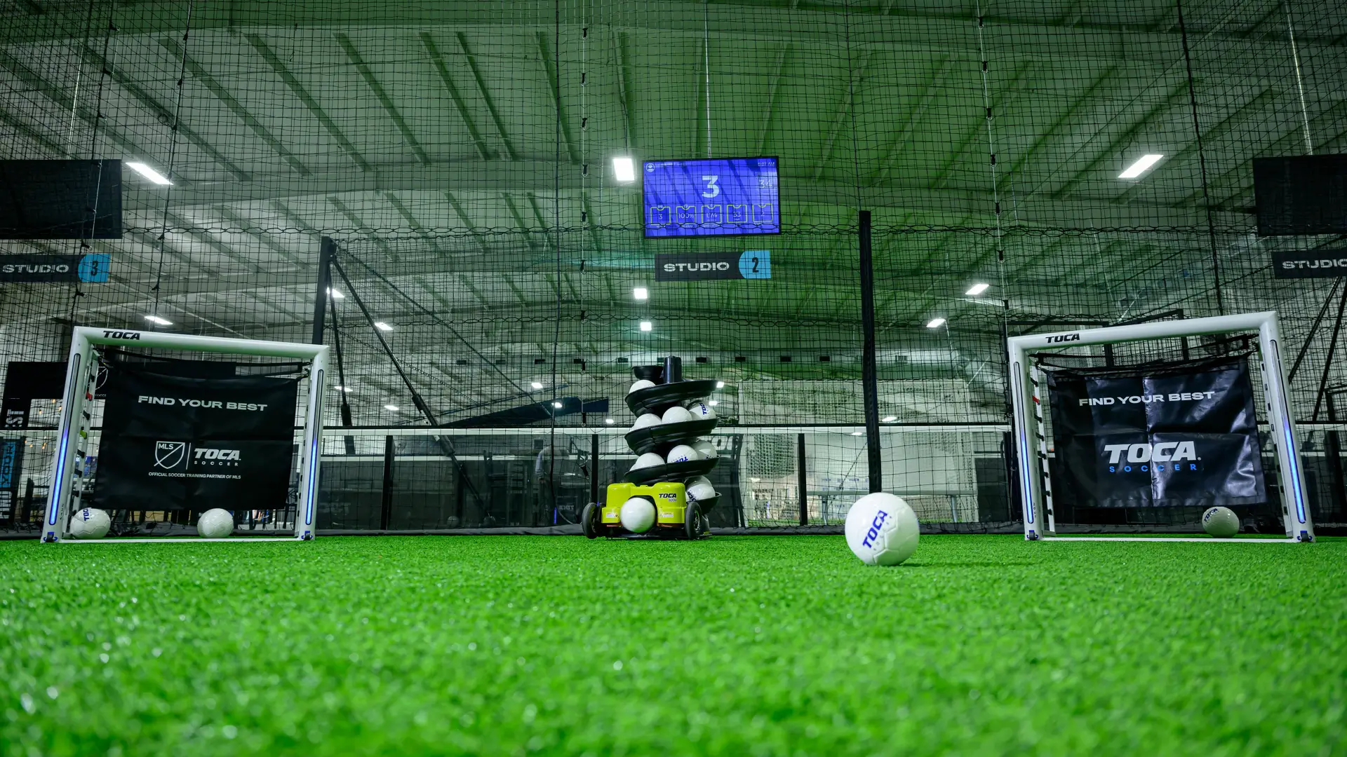 TOCA Soccer Touch Trainer machines and goals set up on indoor turf inside a TOCA training facility