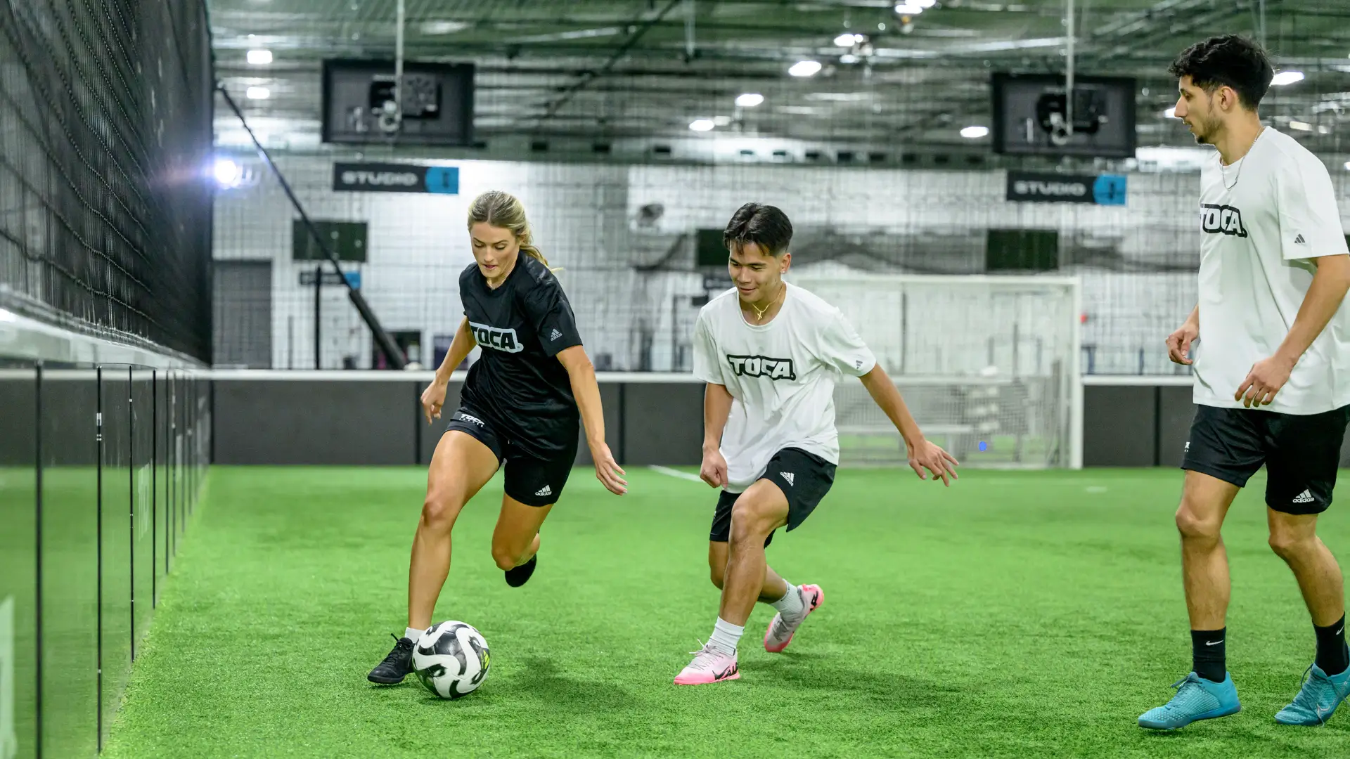 Small group of players in TOCA Soccer jerseys competing for the ball during an indoor training session