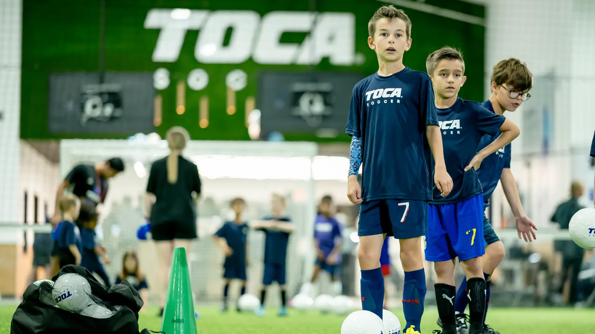 Young players in TOCA Soccer jerseys waiting their turn during a youth soccer drill at a TOCA facility
