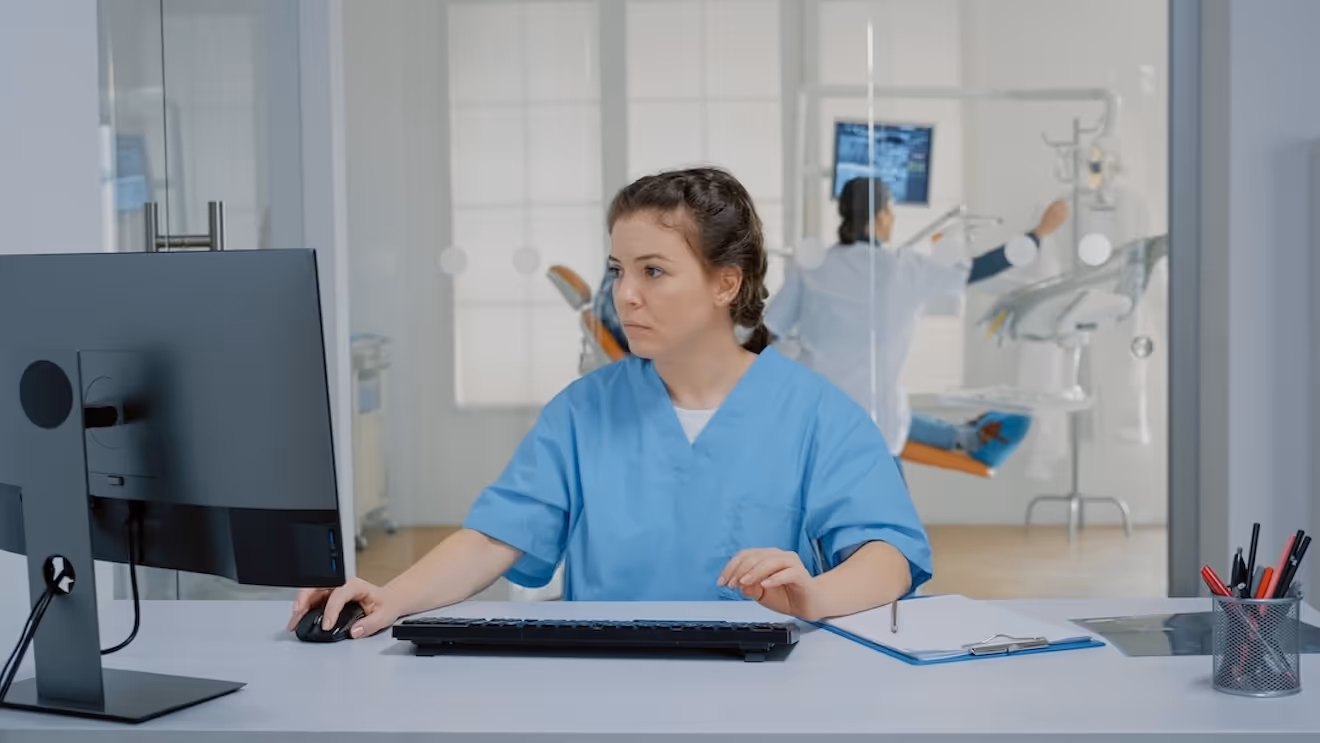 Mitarbeiterin einer Zahnarztpraxis sitzt am PC.