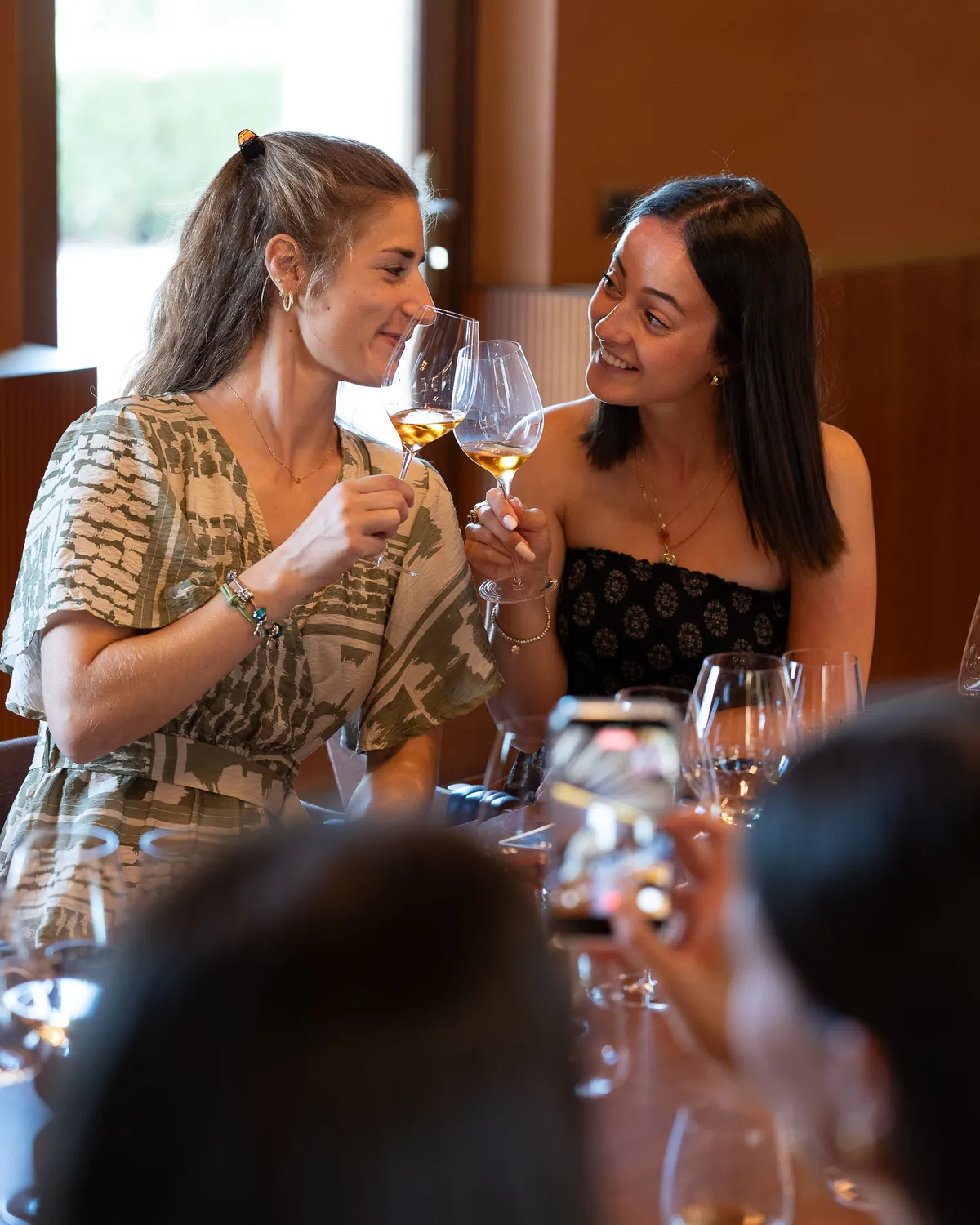 Two friends toast with a glass of white wine in the Ermacora tasting room
