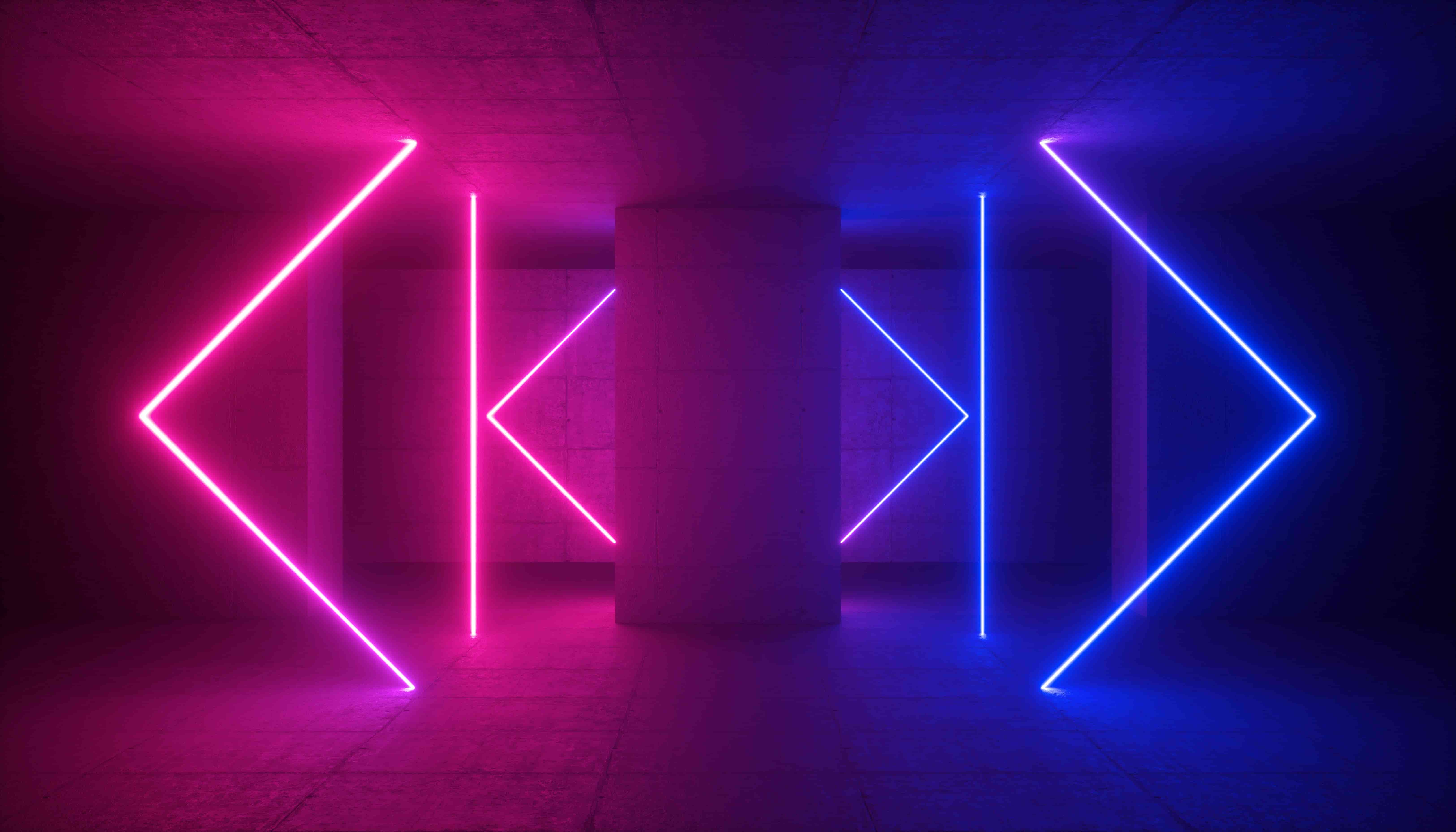 Dark tunnel with neon pink and blue geometric light shapes on either side of a central concrete pillar.