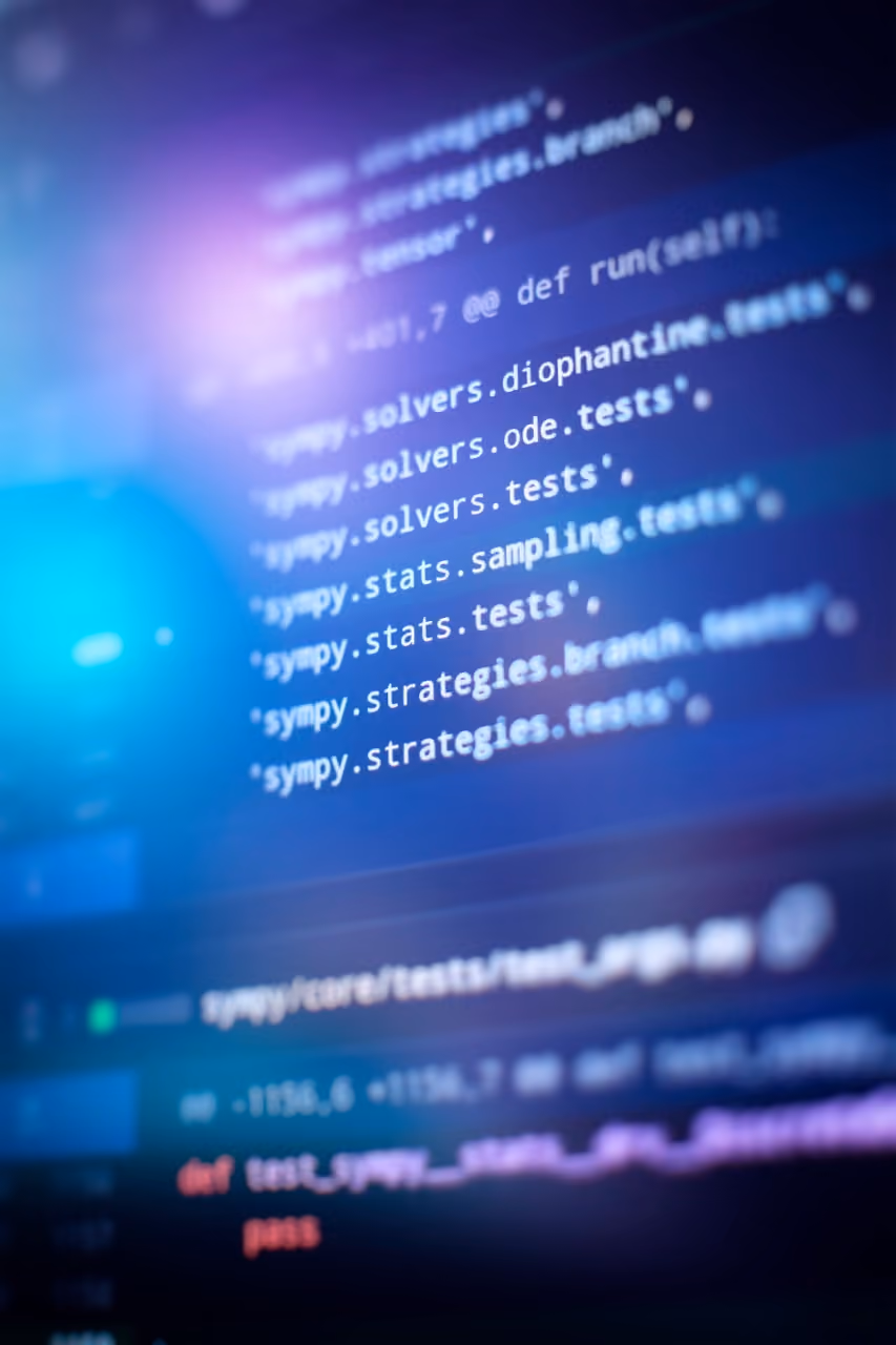 Close-up of a computer screen displaying blurry Python code with blue and purple light reflections.