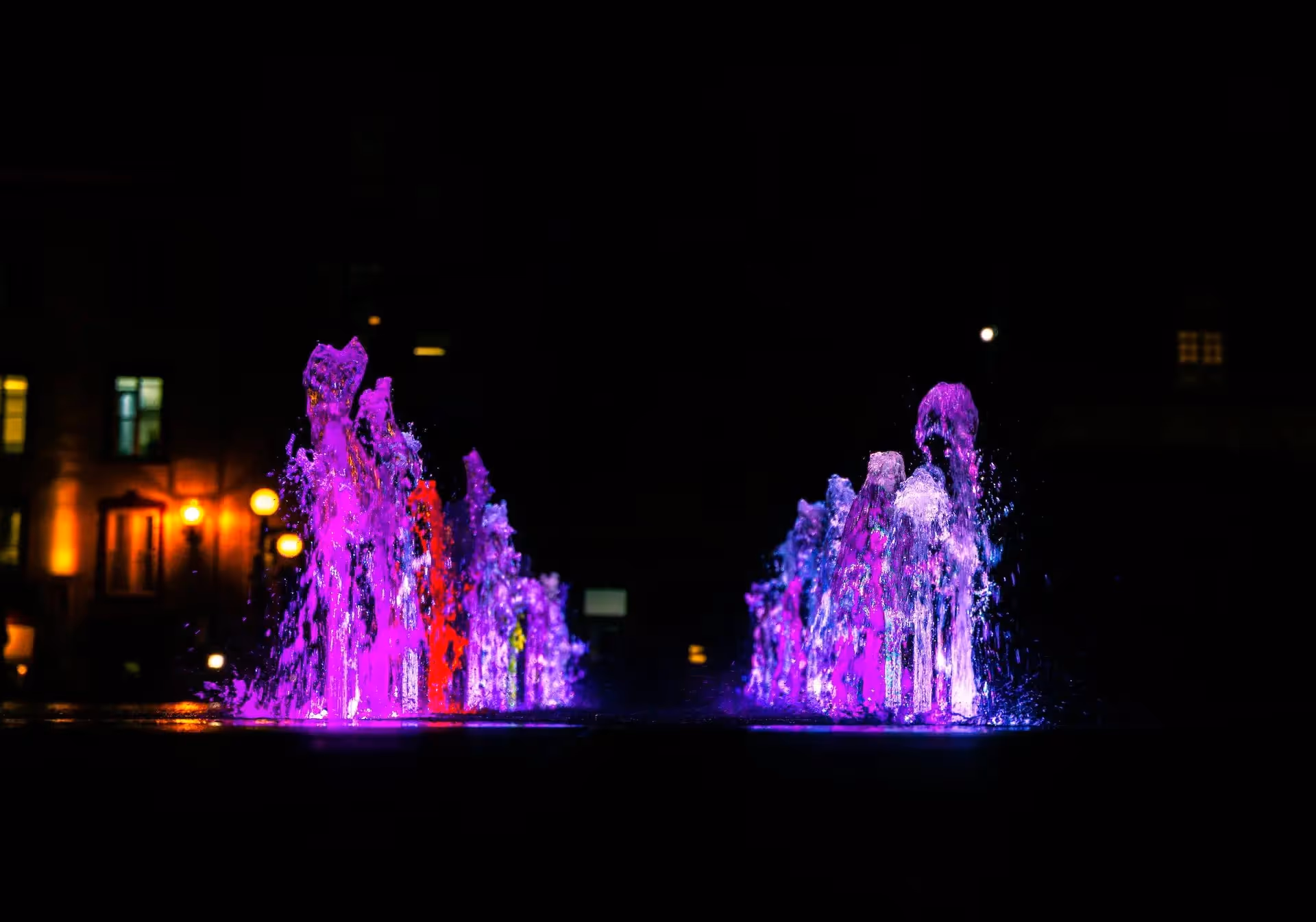 Colorful fountains erupting from a lake at night 