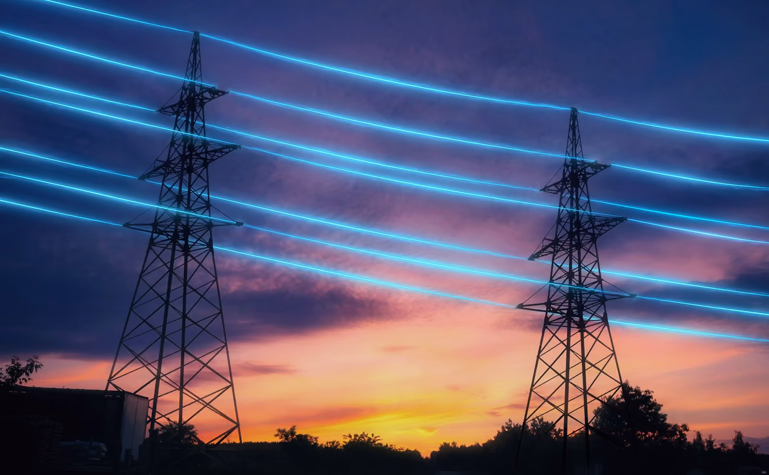 Two power transmission towers with glowing blue electrical lines at sunset with colorful sky.