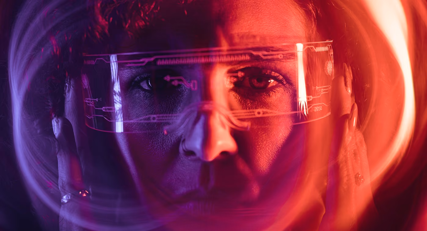 Face of a person wearing translucent futuristic glasses with digital circuit patterns and colorful light trails.