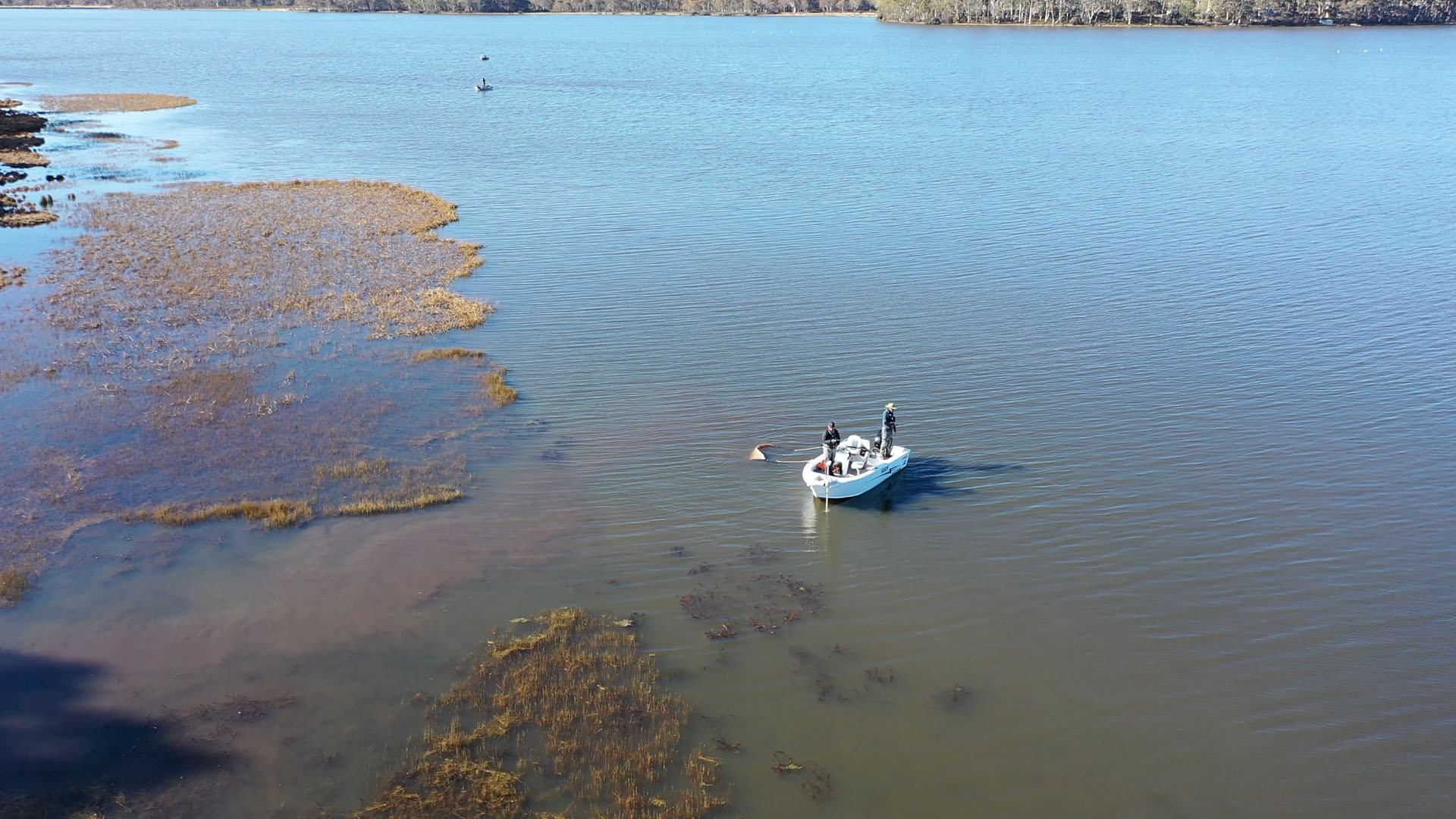aerial shot of men in boat on open water at penstock lagoon