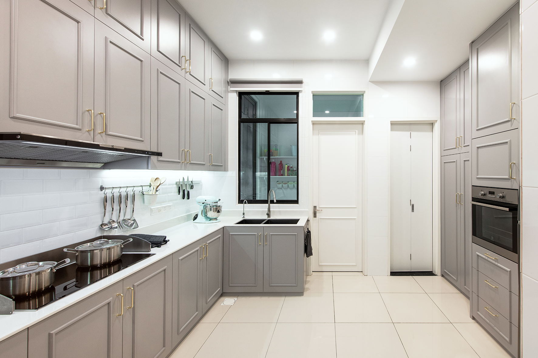 Kitchen in grey cabinets, gold handles and white quartz top.