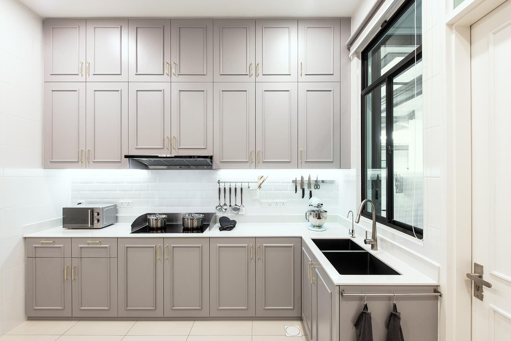 Kitchen in grey cabinets, gold handles and white quartz top.