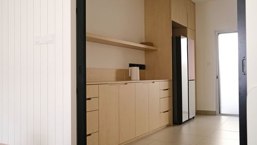 A kitchen with a refrigerator and a wooden cabinet.