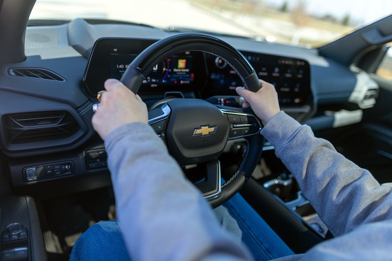 A closeup of a person's hands on the steering wheel of a Chevy EV truck
