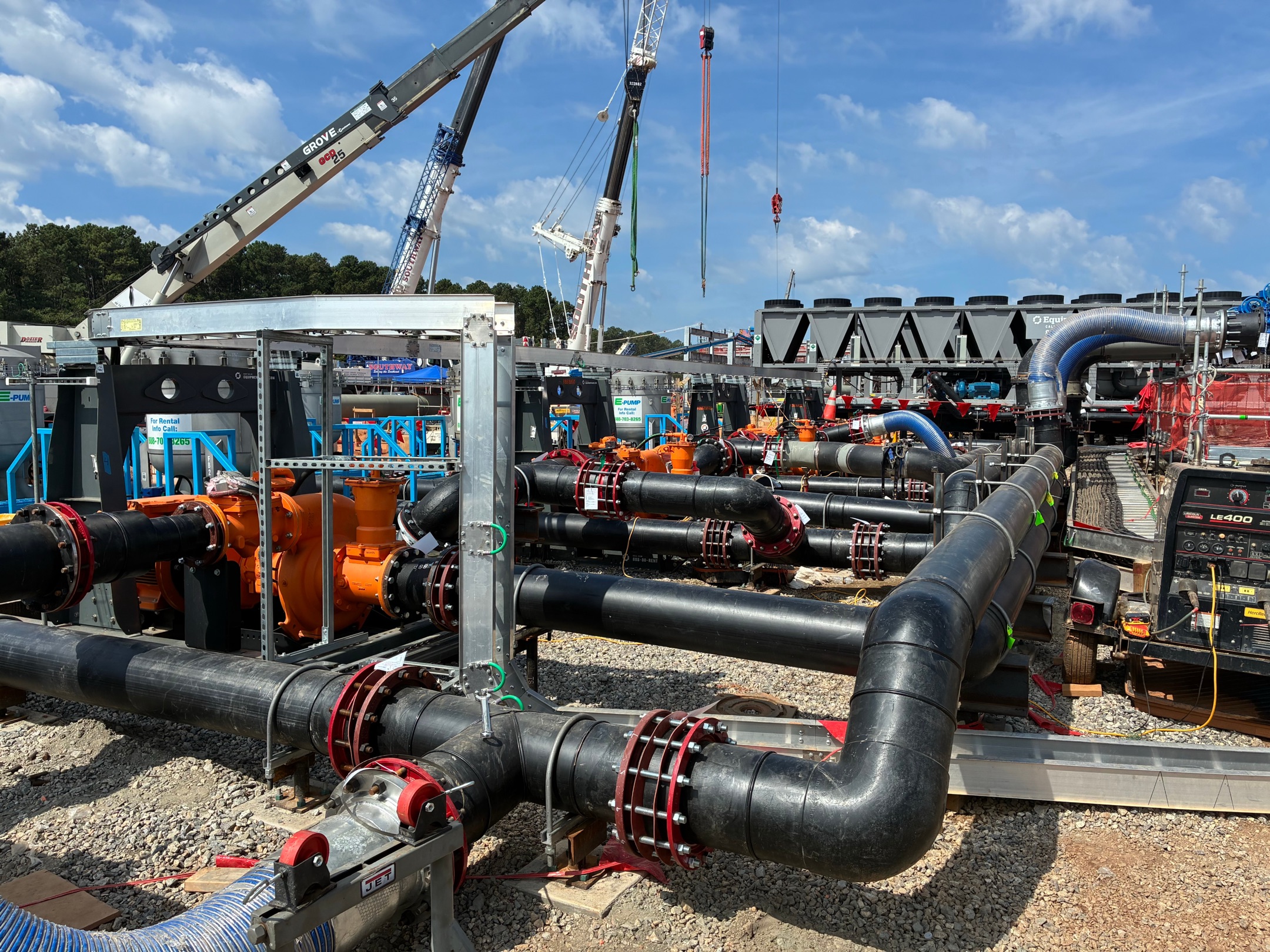 Large-diameter pipe manifold and pumps staged on a jobsite