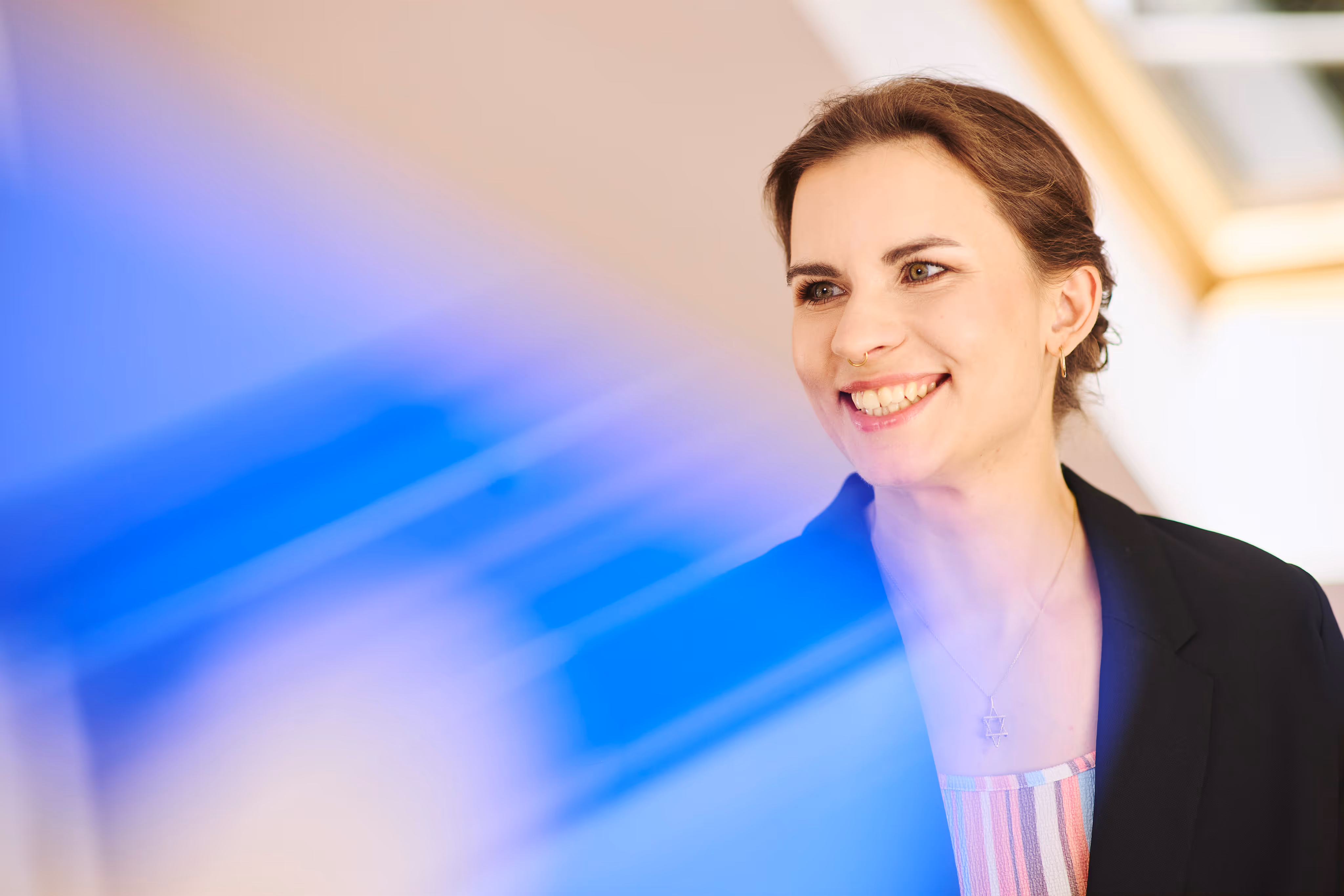 Portrait einer jungen Frau mit dunklem Blazer, die freundlich in die Kamera lächelt