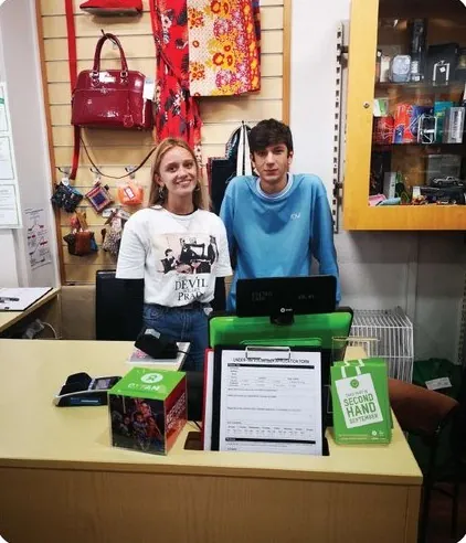Two ILC students volunteering at a charity shop counter