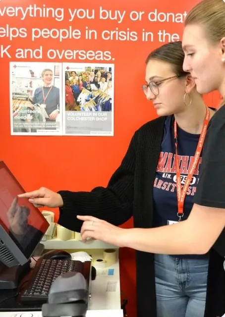 ILC students learning to use the till in a charity shop