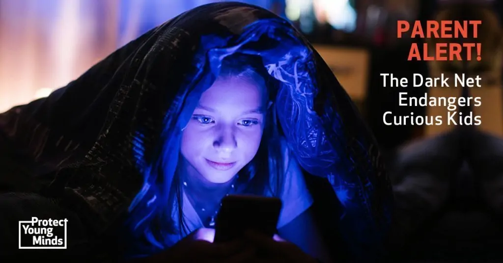 A young girl hiding underneath a blanket looking at a smartphone