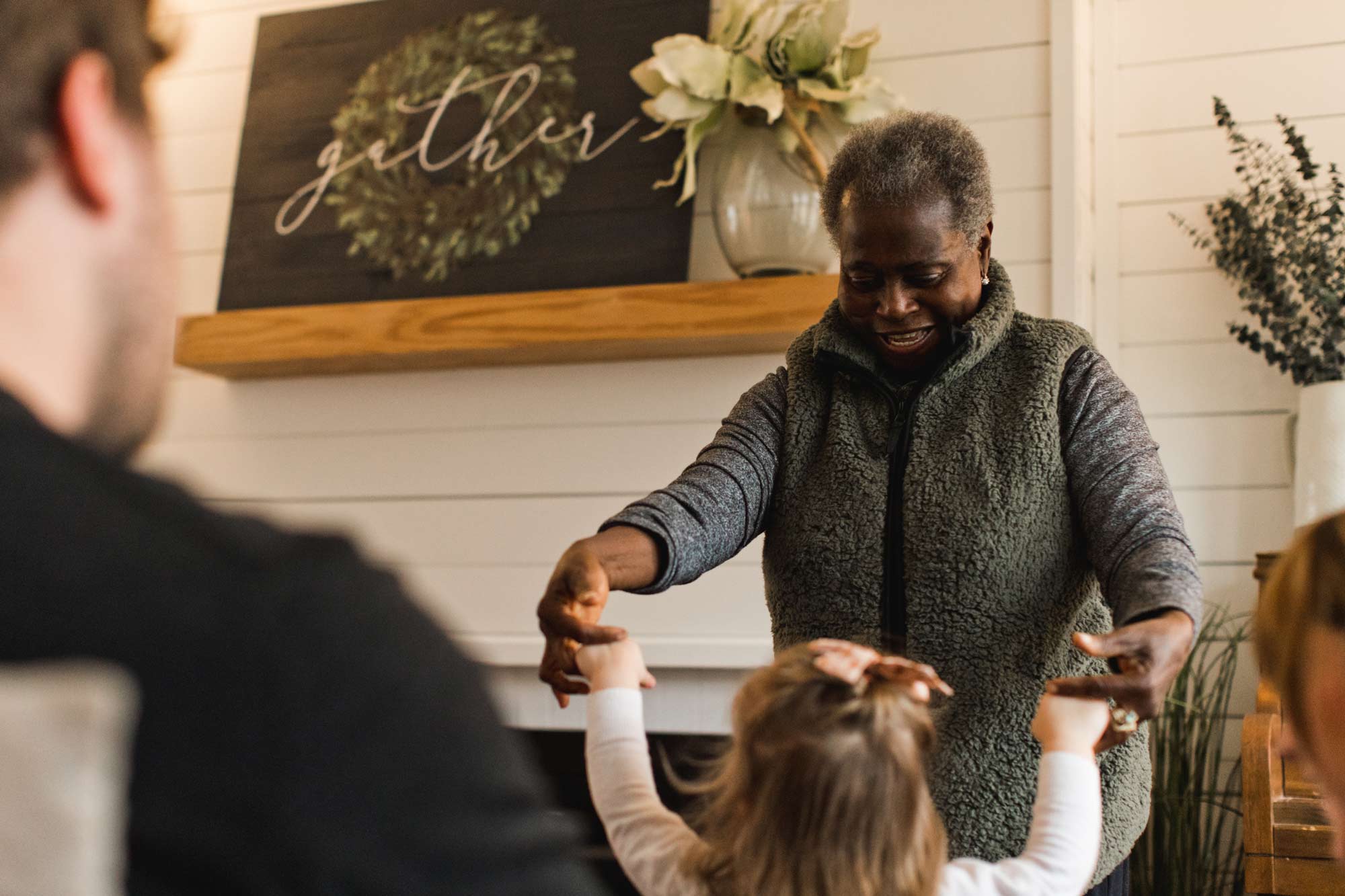 An older woman dancing playfully with a elementary school girl in a kitchen during small group.