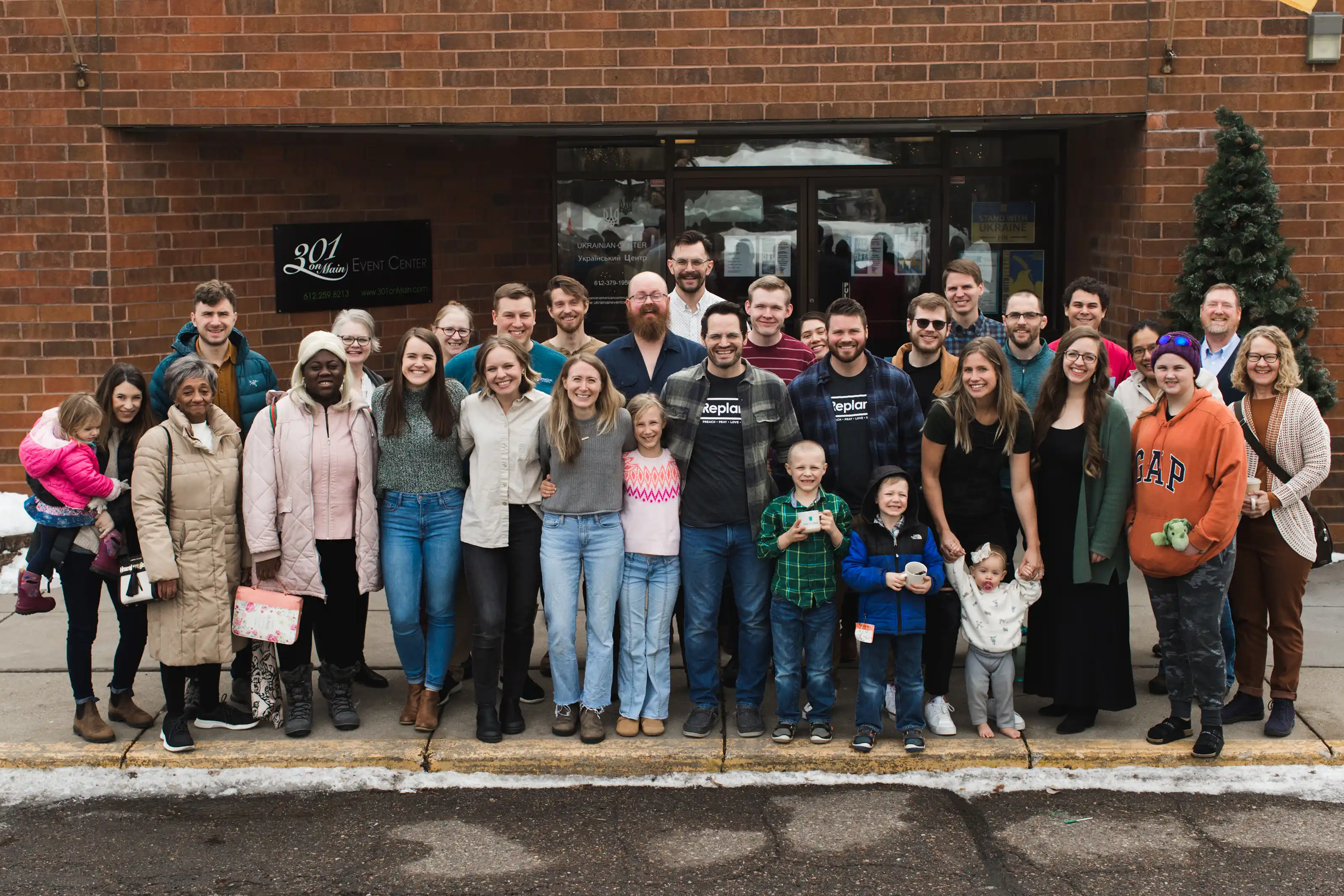 Large group of people of different age, gender, race, and ethnicity standing together excitedly.