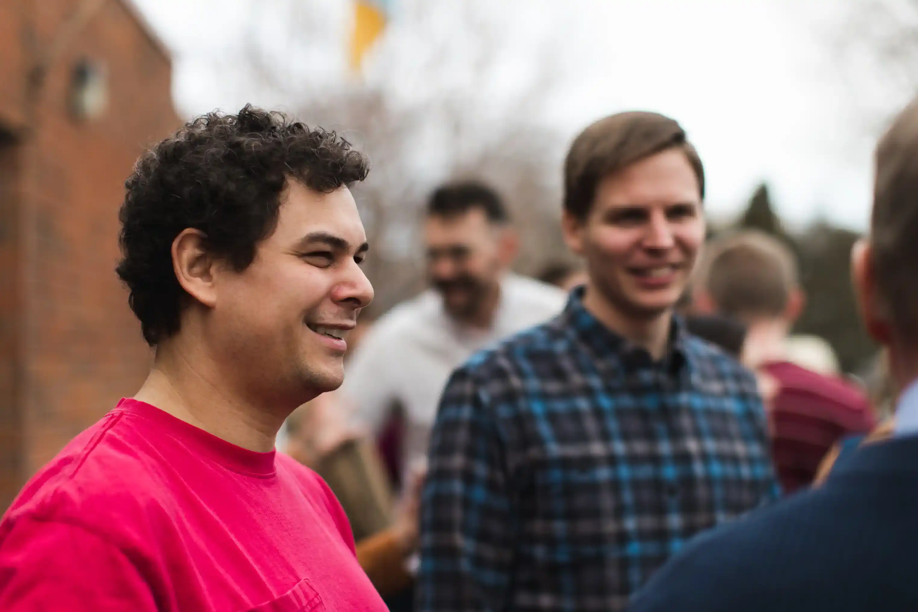 Large group of people of different age, gender, race, and ethnicity standing together excitedly.