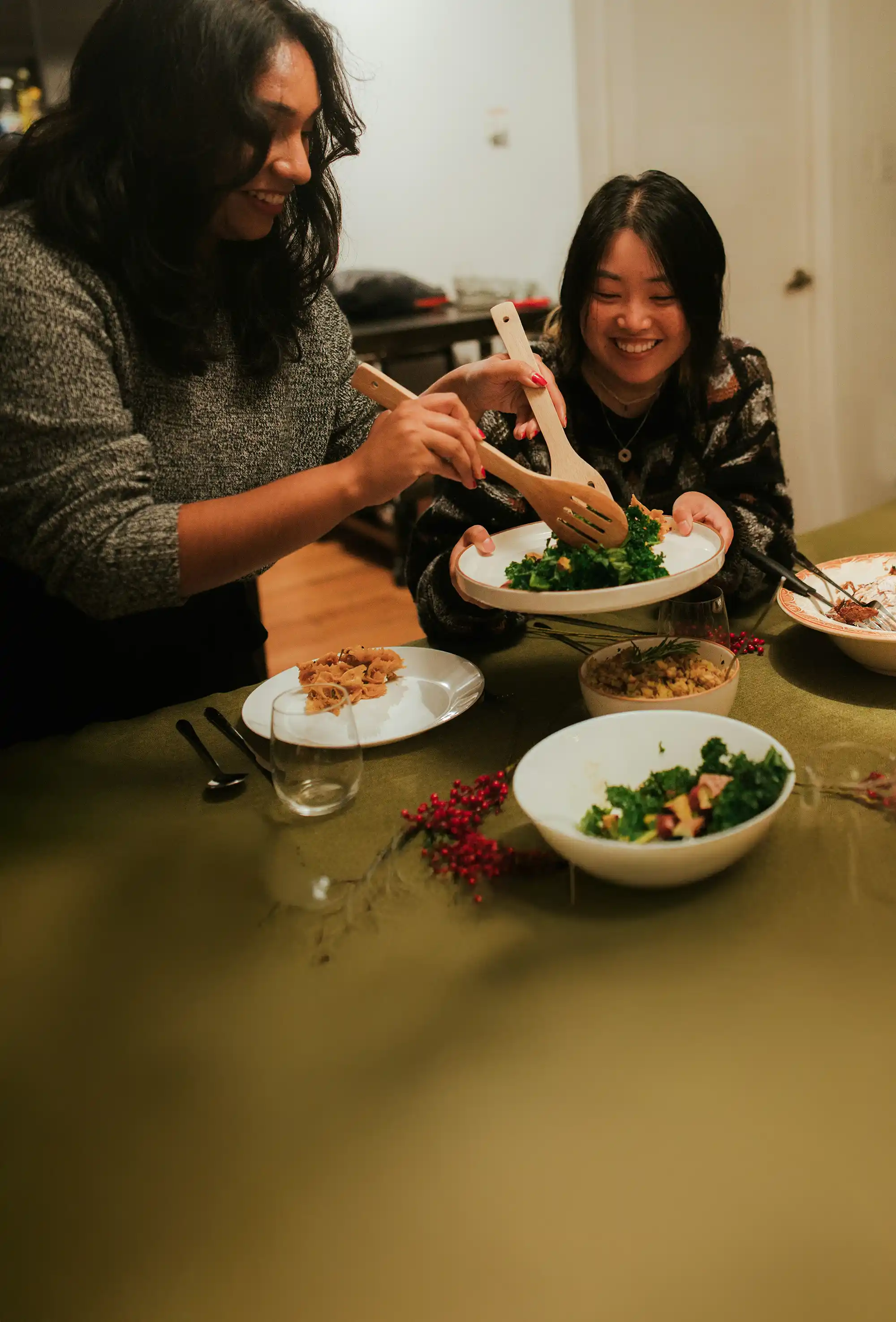 Two young women serving a salad at a small group gathering.