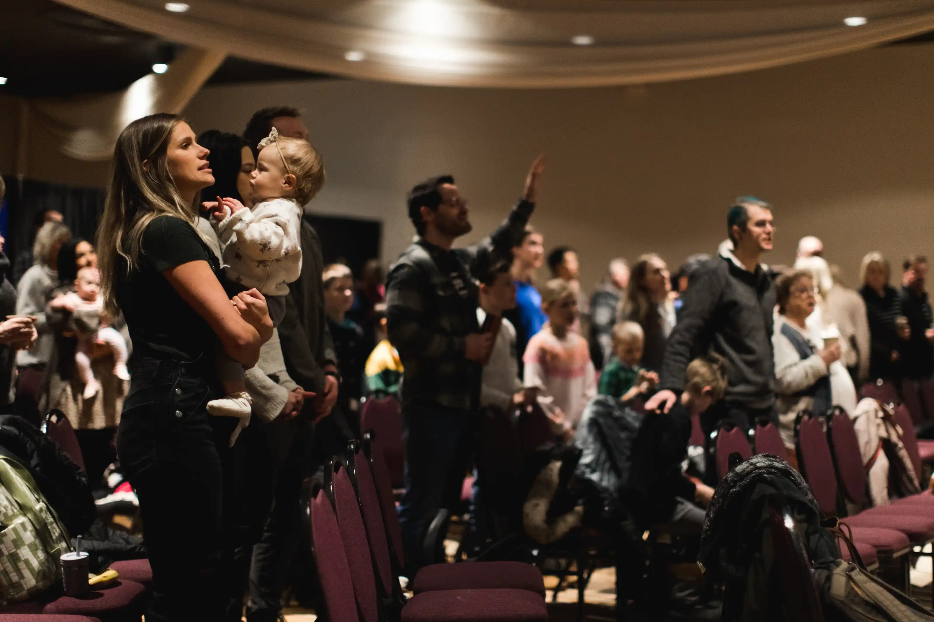 Group of happy people waving in front of a church entrance.