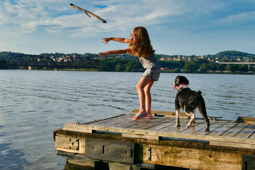 A girl playing fetch with her emotional support dog on the Ohio river.