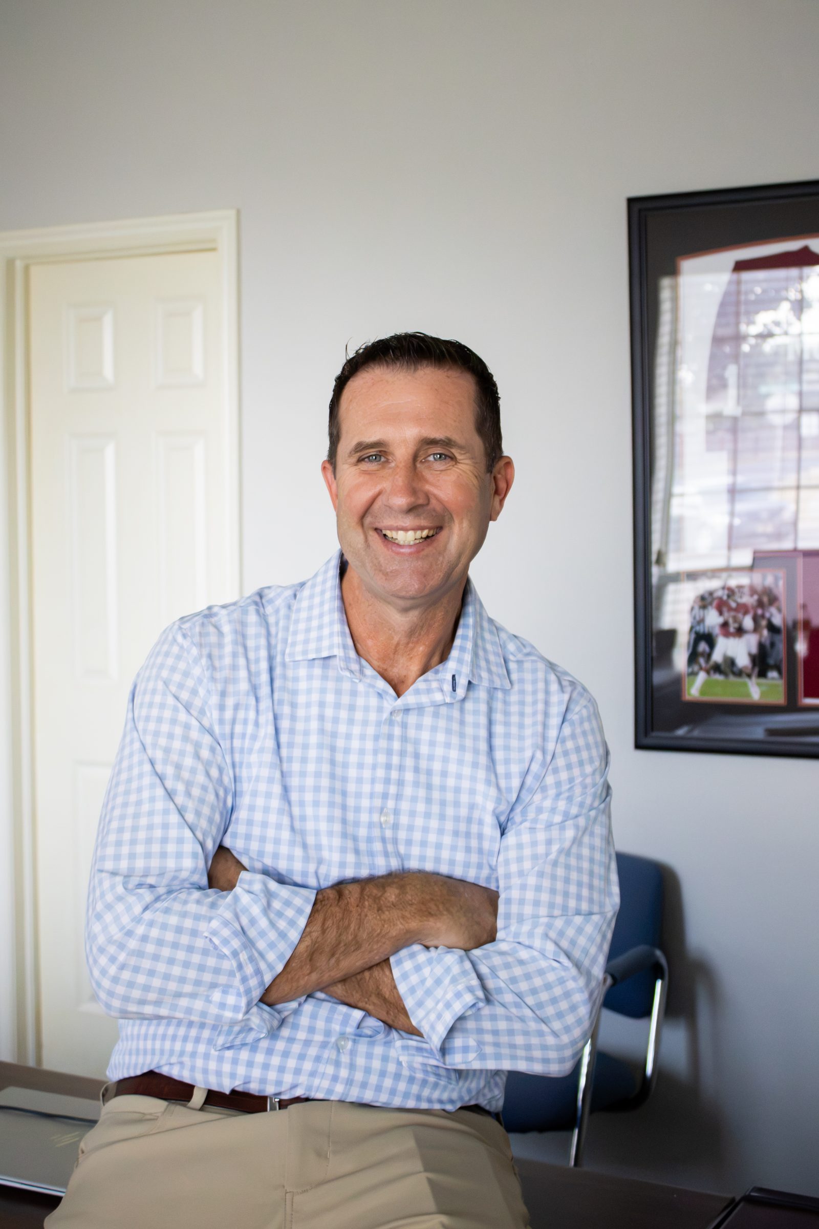 Josh Nelson, Allstate agent, standing with arms crossed in his Norman, OK office