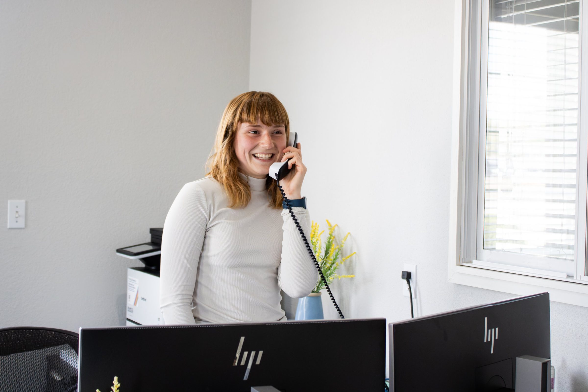Front desk team member laughing on a phone call with a customer