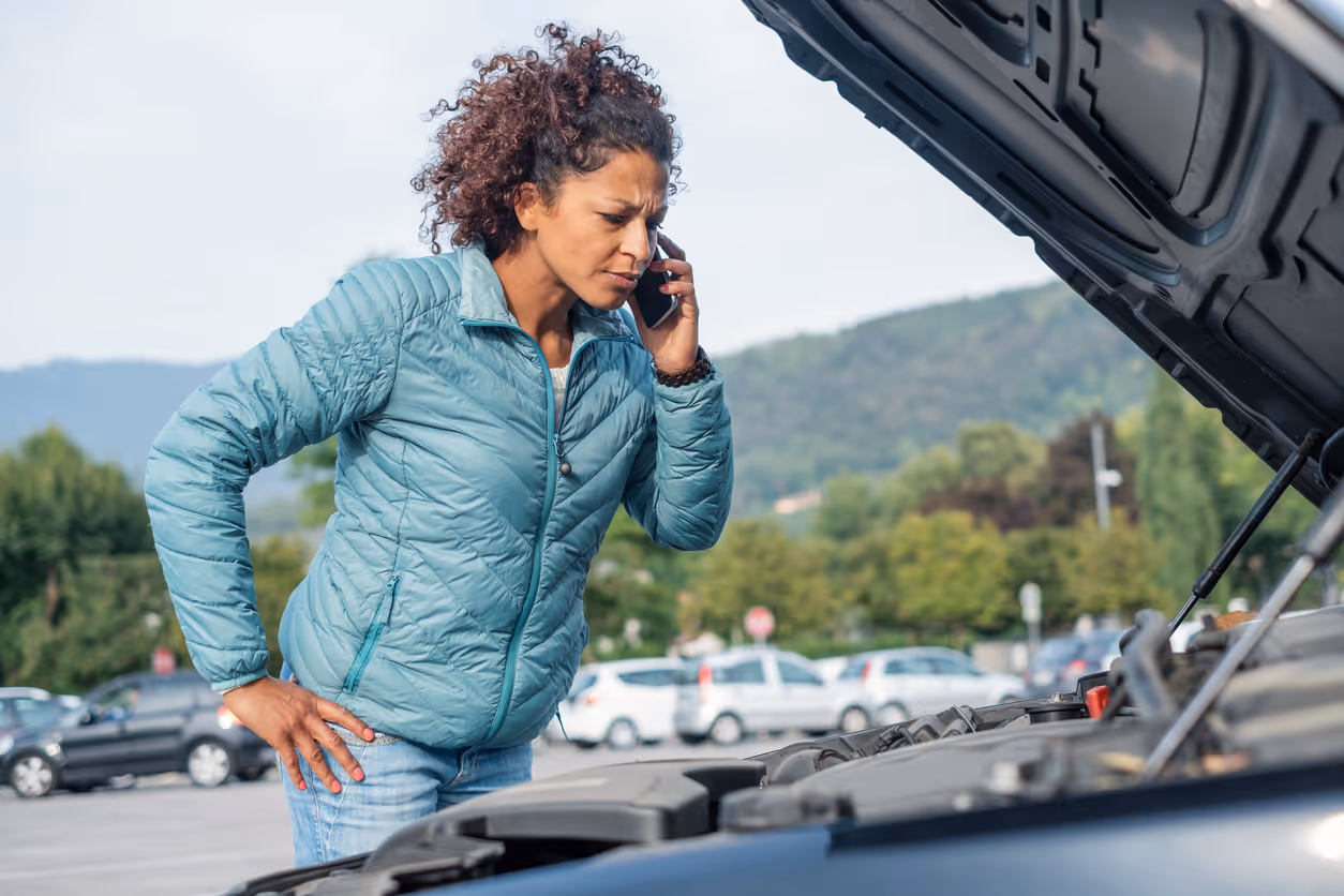 Woman calling a mechanic with car trouble in a parking lot