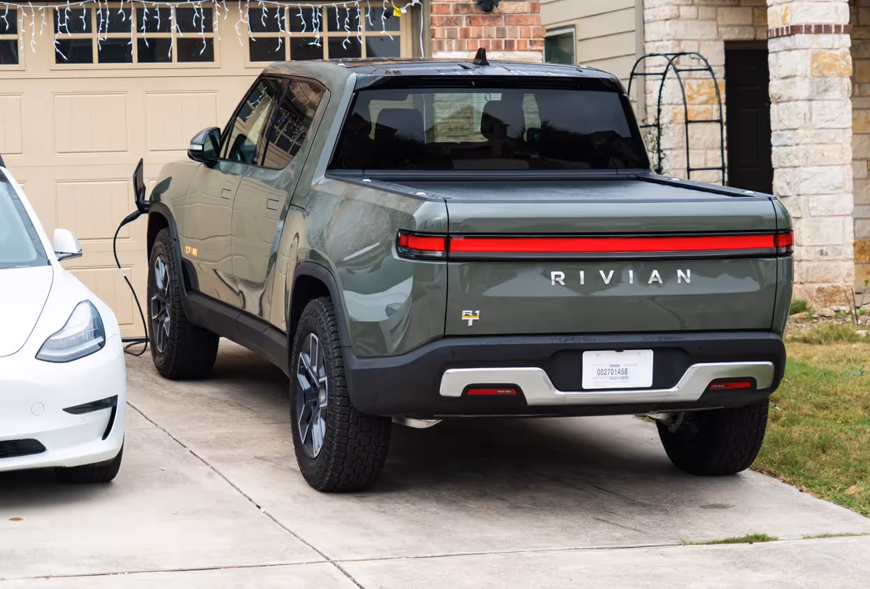 Green Rivian parked in driveway in front of a garage door