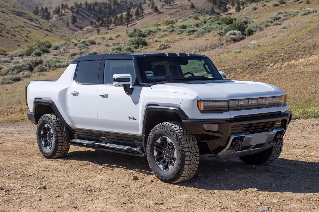 A 2022 GMC Hummer EV in white sits atop a dirt road in the rural backcountry hills.