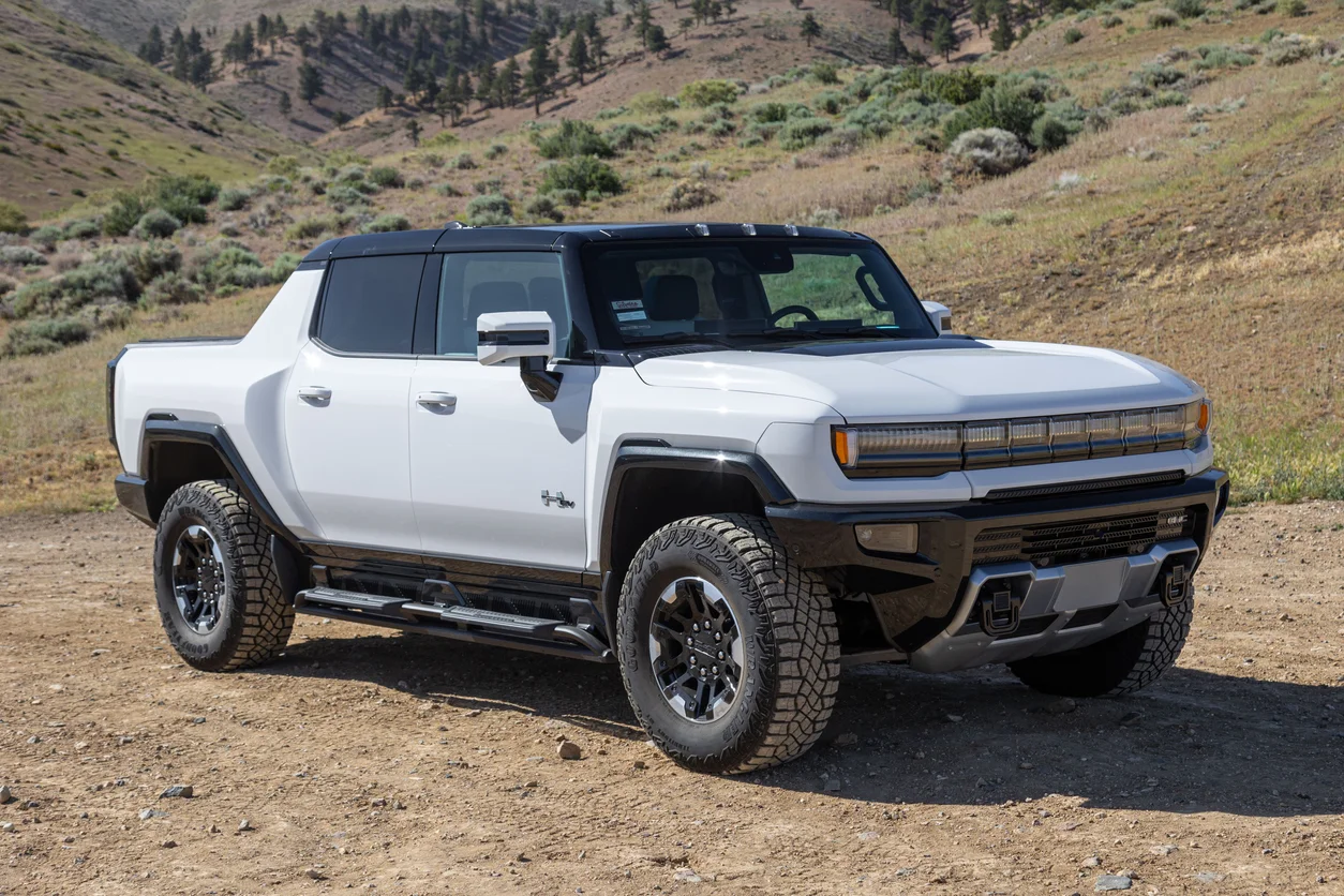 A 2022 GMC Hummer EV in white sits atop a dirt road in the rural backcountry hills.