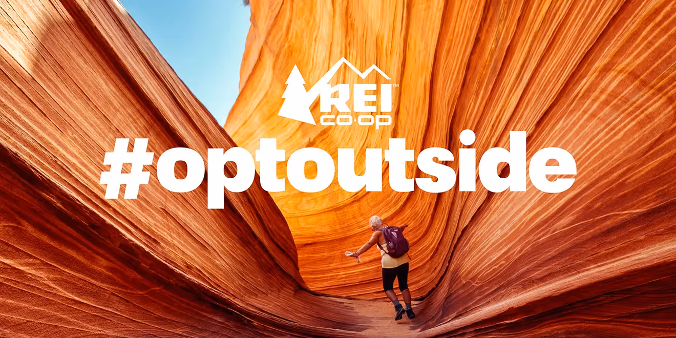 Randonneur explorant un canyon de roche rouge avec le logo de la campagne #OptOutside de REI.