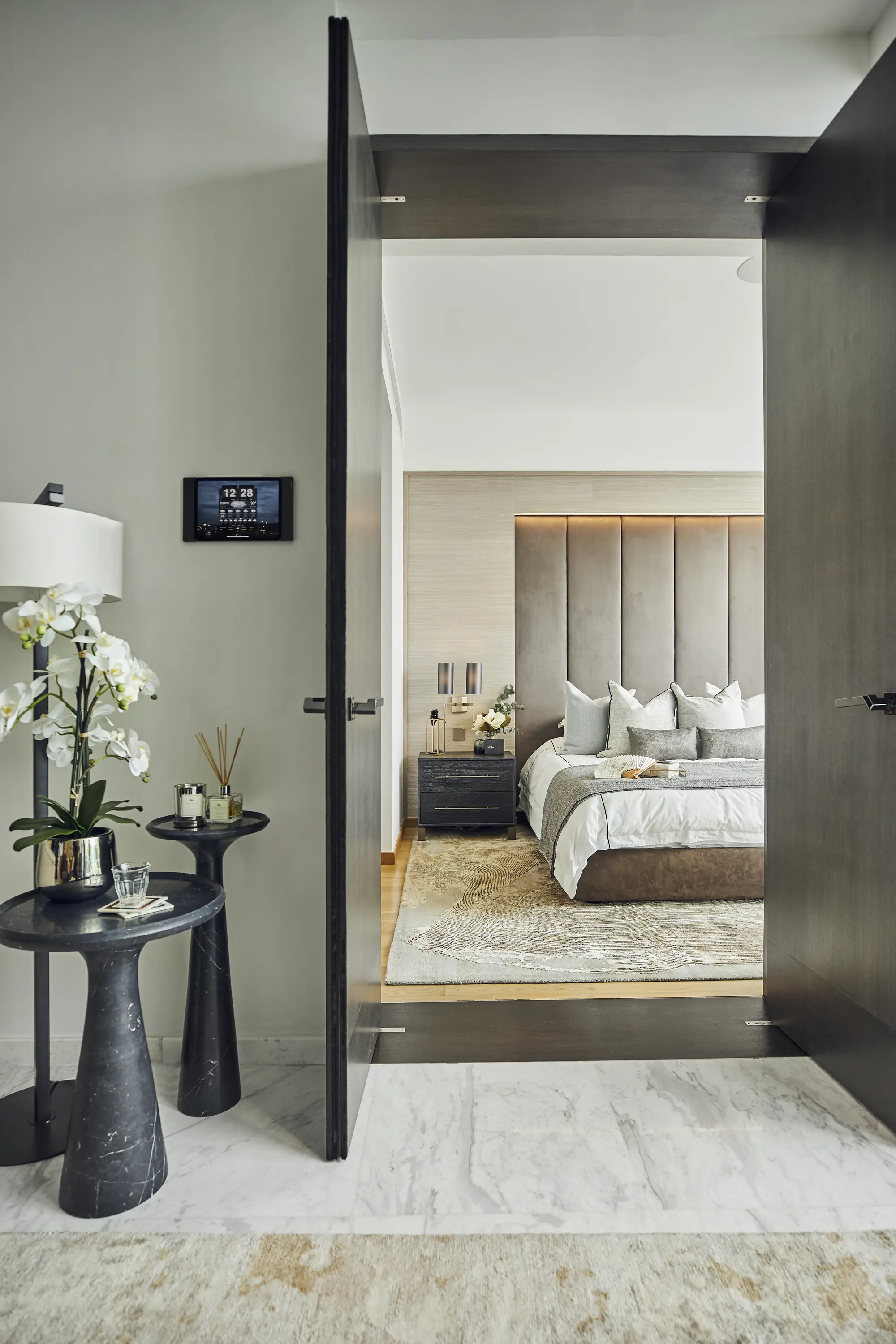 Luxury bedroom viewed through dark timber doors, designed by Elliot James Interiors