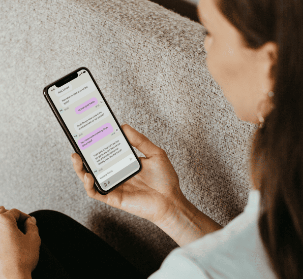 A person looking at their phone. The phone screen is of a conversation