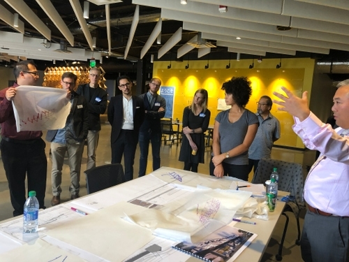 participants at a workshop gesticulate while discussing around a table.