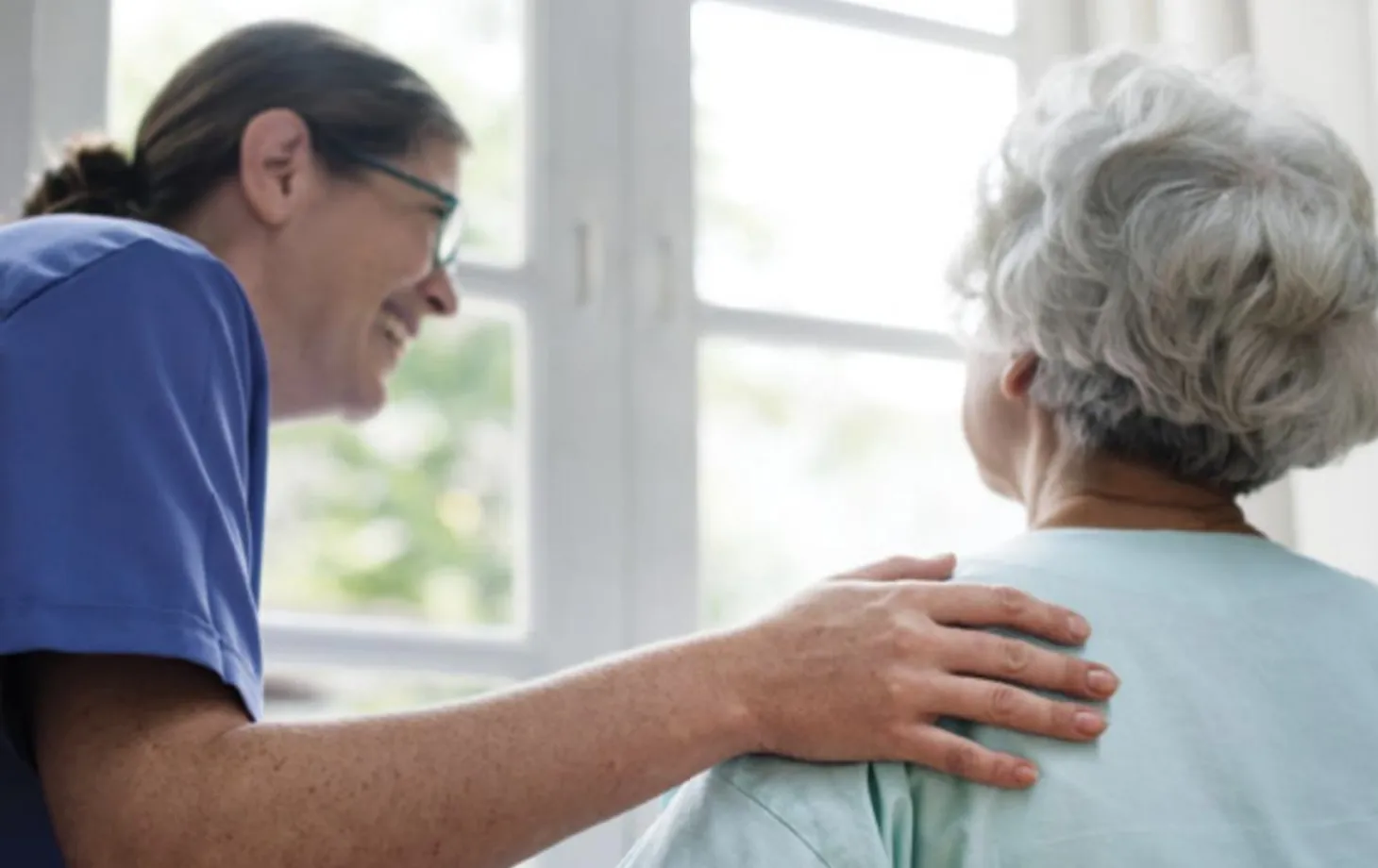 An aged care worker chats with a resident in a bright facility
