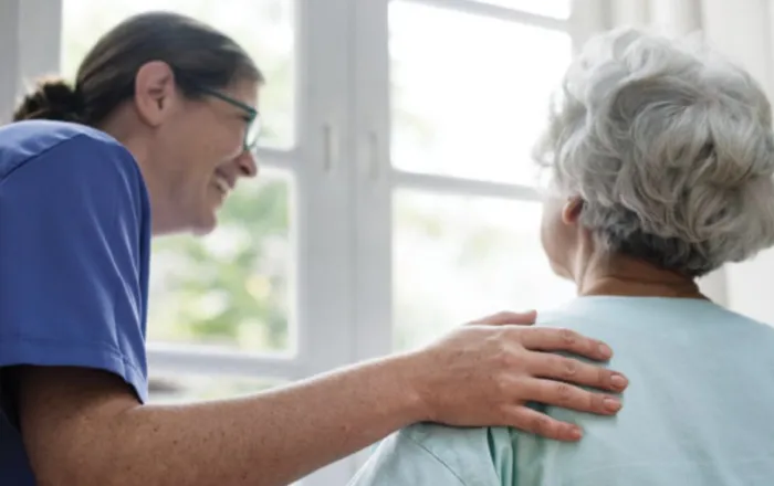 An aged care worker chats with a resident in a bright facility